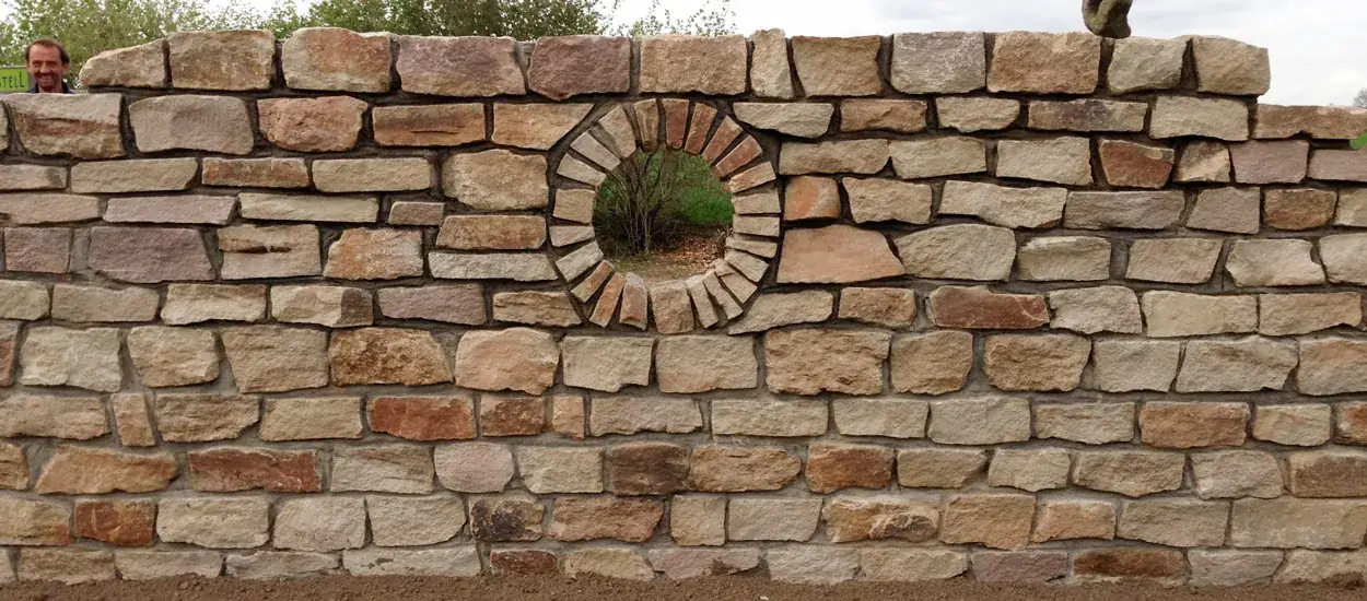 Natursteinmauer mit Rundfenster